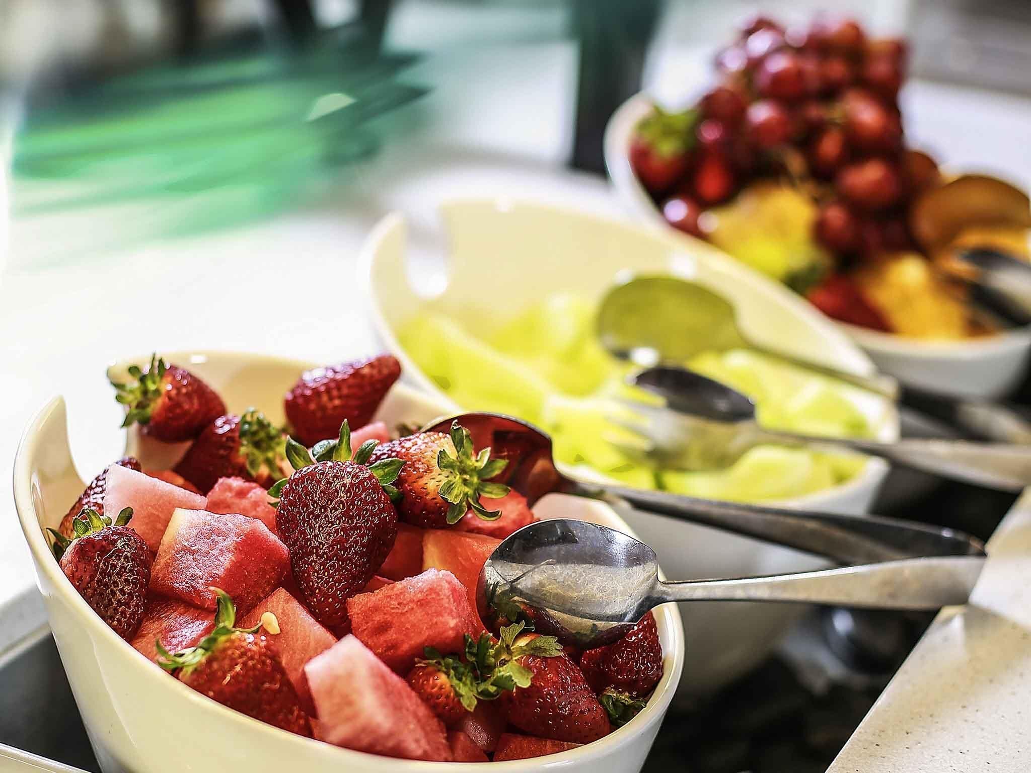 A buffet with various fruits and a spoon.
