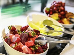 A buffet with various fruits and a spoon. - ibis Sydney World Square (Sydney)