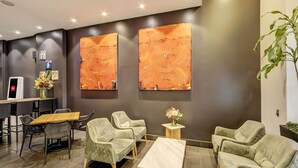 Un moderno vestíbulo de hotel con una recepción, una zona de estar y dos grandes cuadros abstractos en la pared.