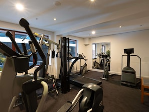 A gym with various exercise equipment, large windows, and a mirror.