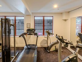 Un gimnasio con cintas de correr, elípticas y equipo de levantamiento de pesas.