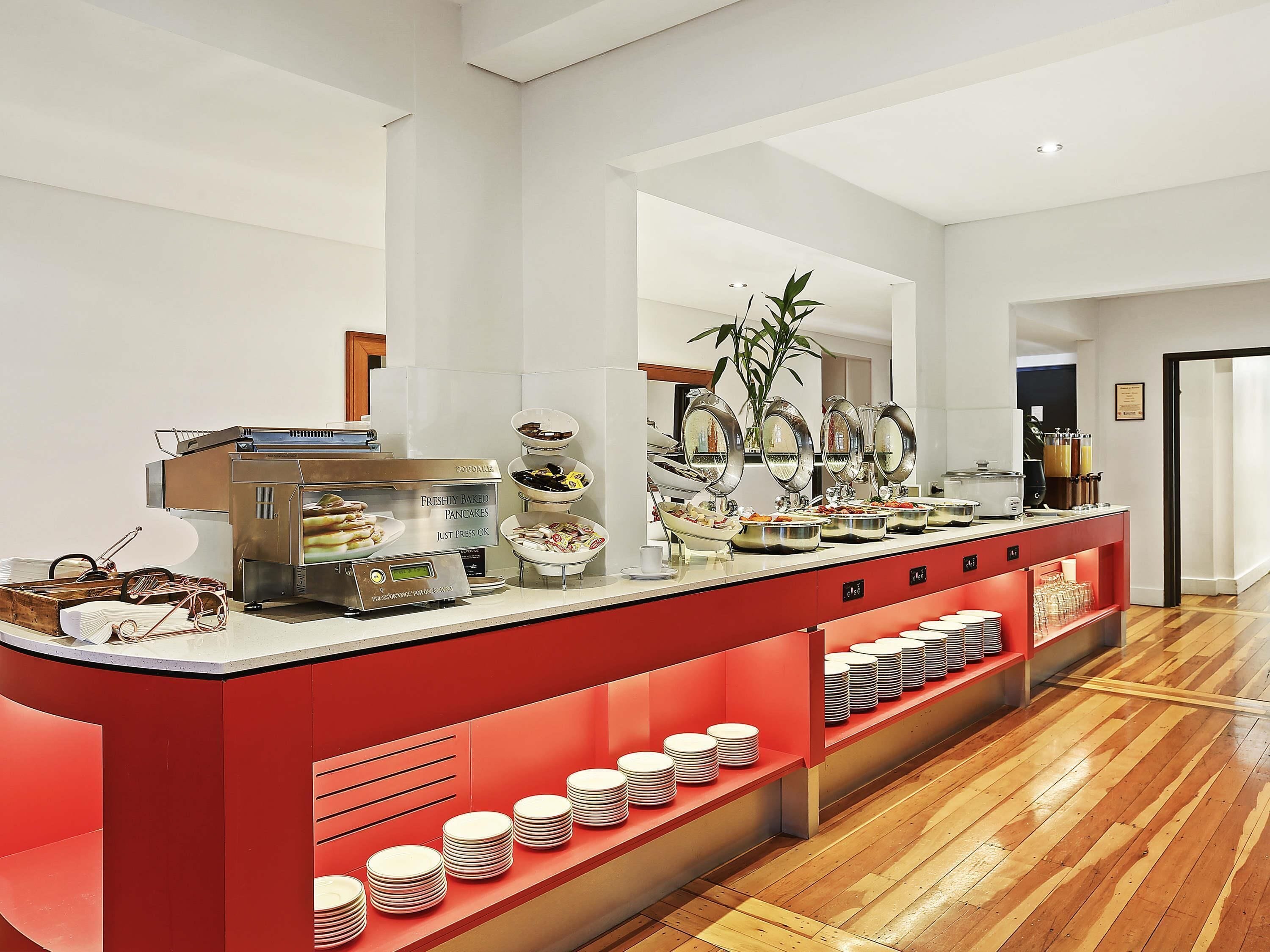 A buffet setup with a variety of food items, a coffee machine, and a plant.