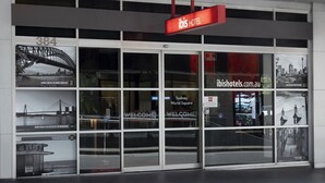 El exterior del hotel ibis World Square con un llamativo letrero rojo, amplias ventanas de vidrio y vistas al Puente de Sydney.