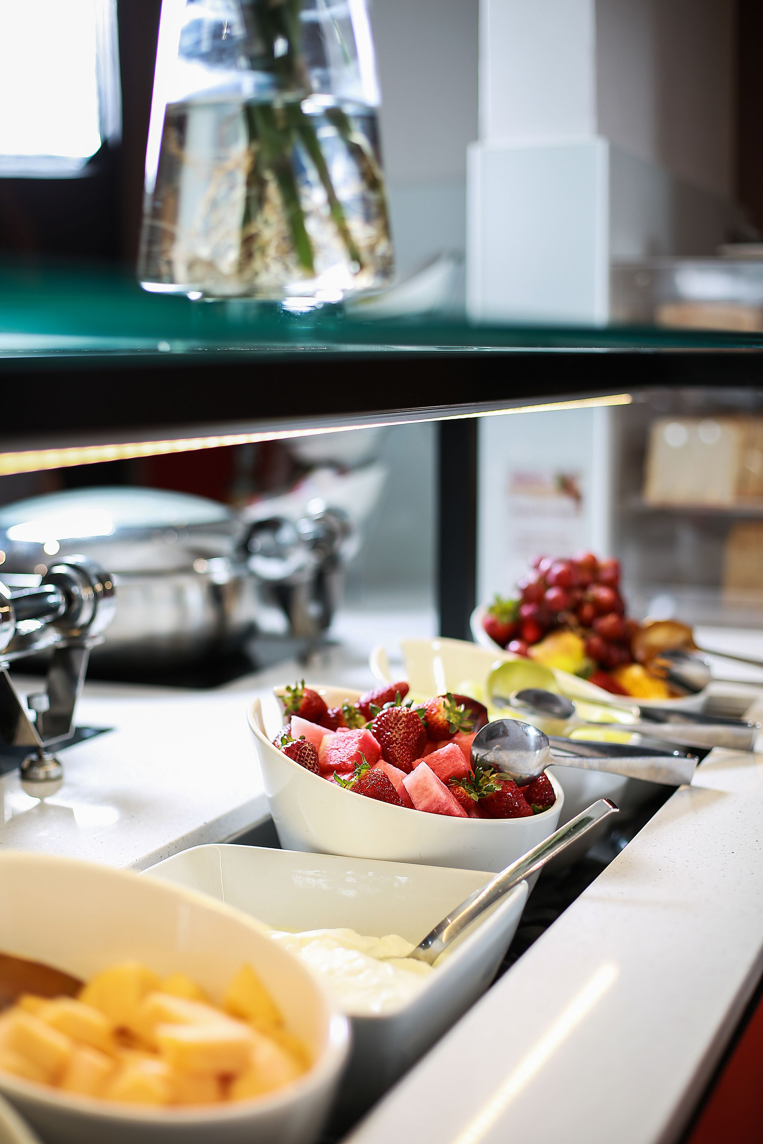 Een buffet met diverse soorten eten, waaronder fruit en een schaal met aardbeien.
