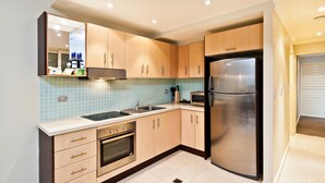 Una cocina moderna con armarios de madera, un refrigerador de acero inoxidable, un horno empotrado y un salpicadero de azulejos.