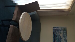 Ein Zimmer mit einem runden Holztisch, zwei braunen Stühlen, einem grauen Sofa und einem Bild an der Wand.