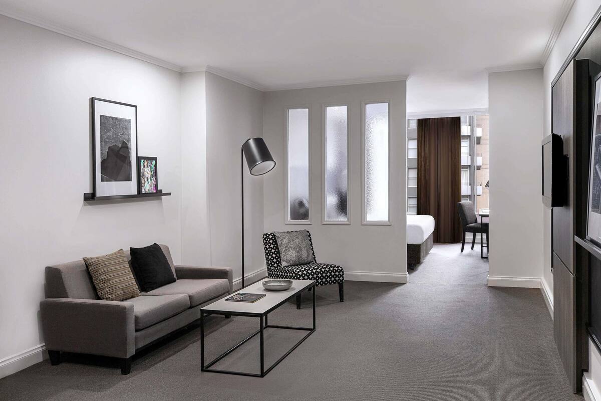 A modern living room with a sofa, coffee table, floor lamp, and a patterned armchair.