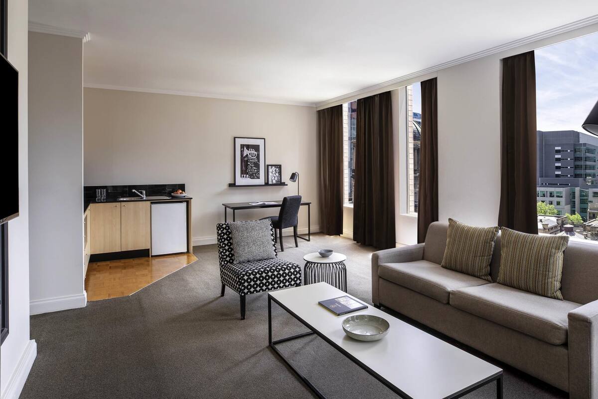 A modern living room with a sofa, coffee table, and a dining area with a chair and a small table.