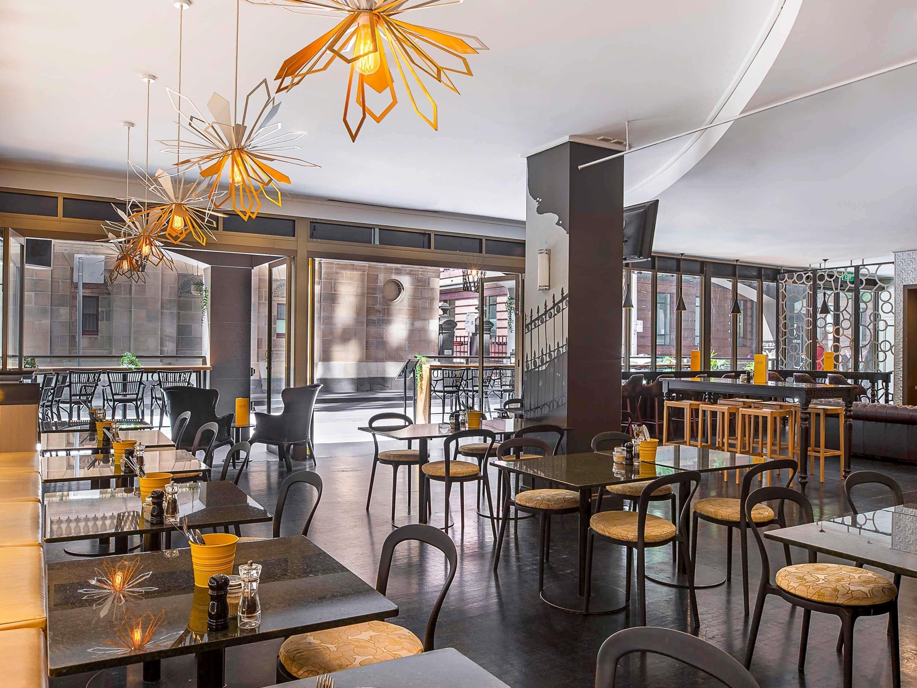 A modern dining area with tables, chairs, and unique hanging light fixtures.