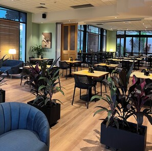 A spacious indoor area with multiple tables and chairs, large windows, and potted plants. - Comfort Inn Grafton (Grafton)