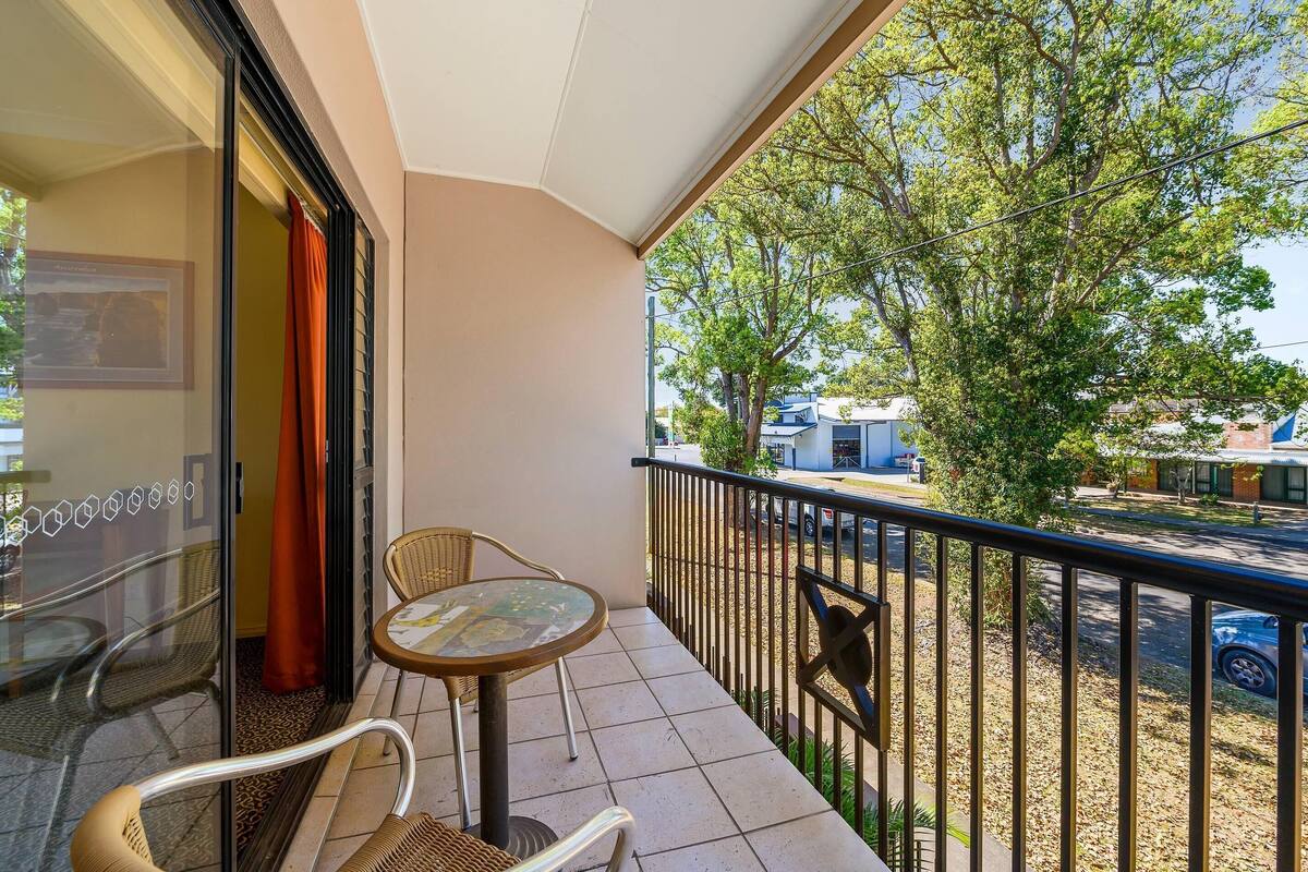 A balcony with a glass door, a small table, and two wicker chairs.