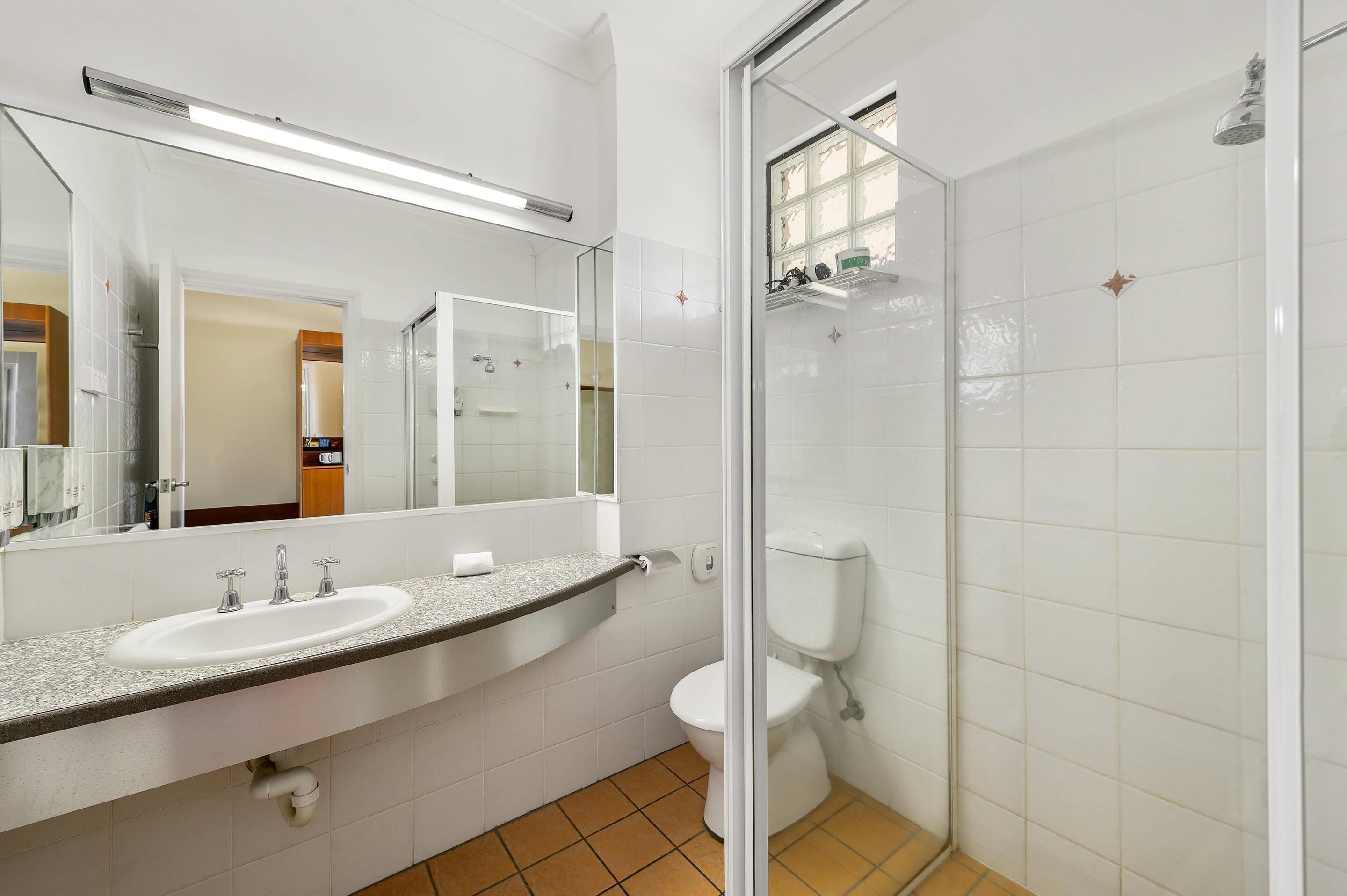 A bathroom with a white sink, mirror, and toilet.