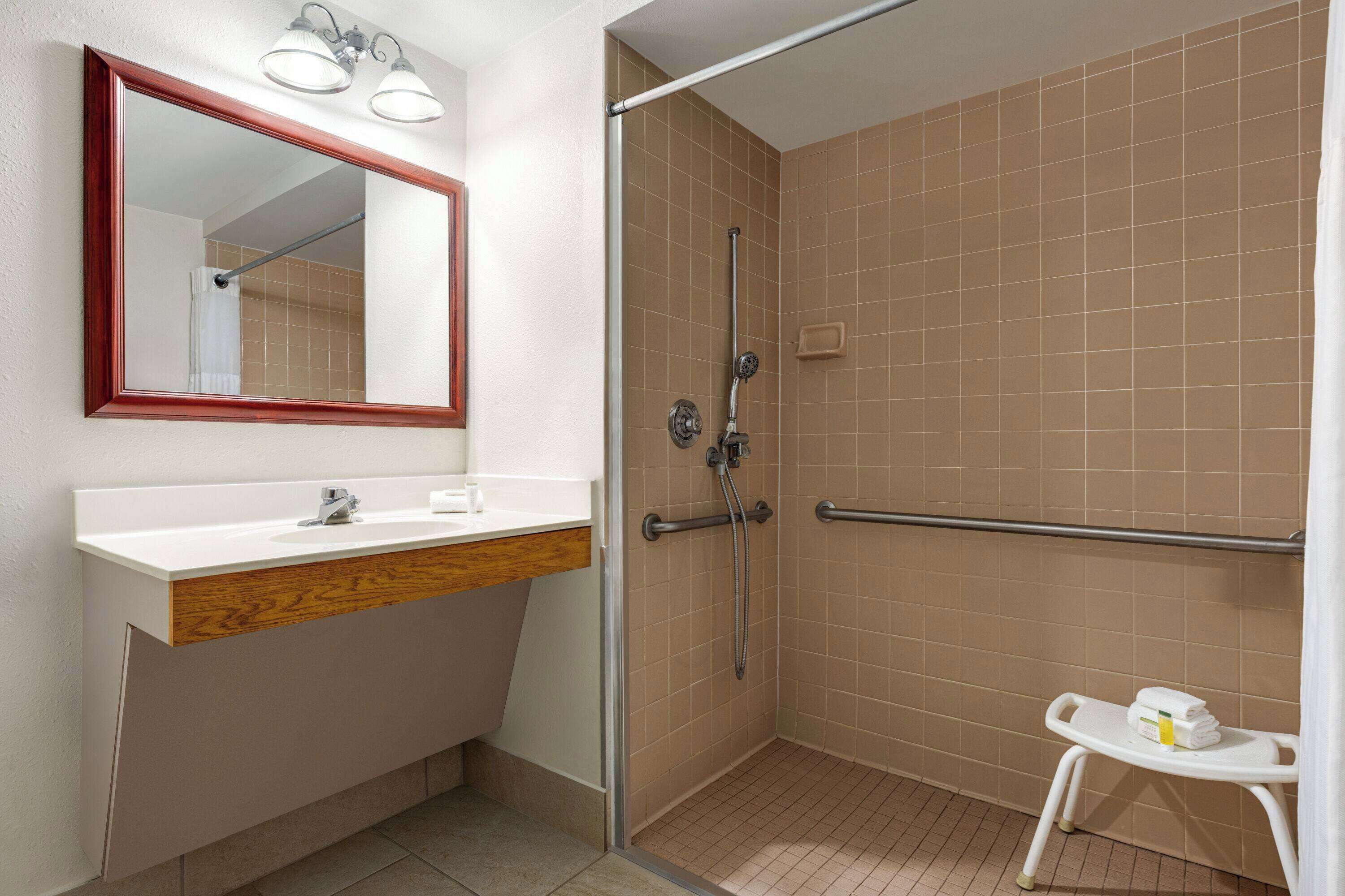 A bathroom with a white sink, mirror, and shower.