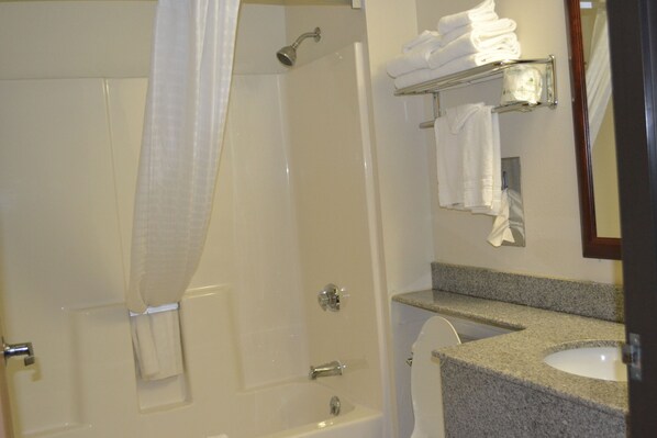Un baño con ducha, lavabo y toallero.