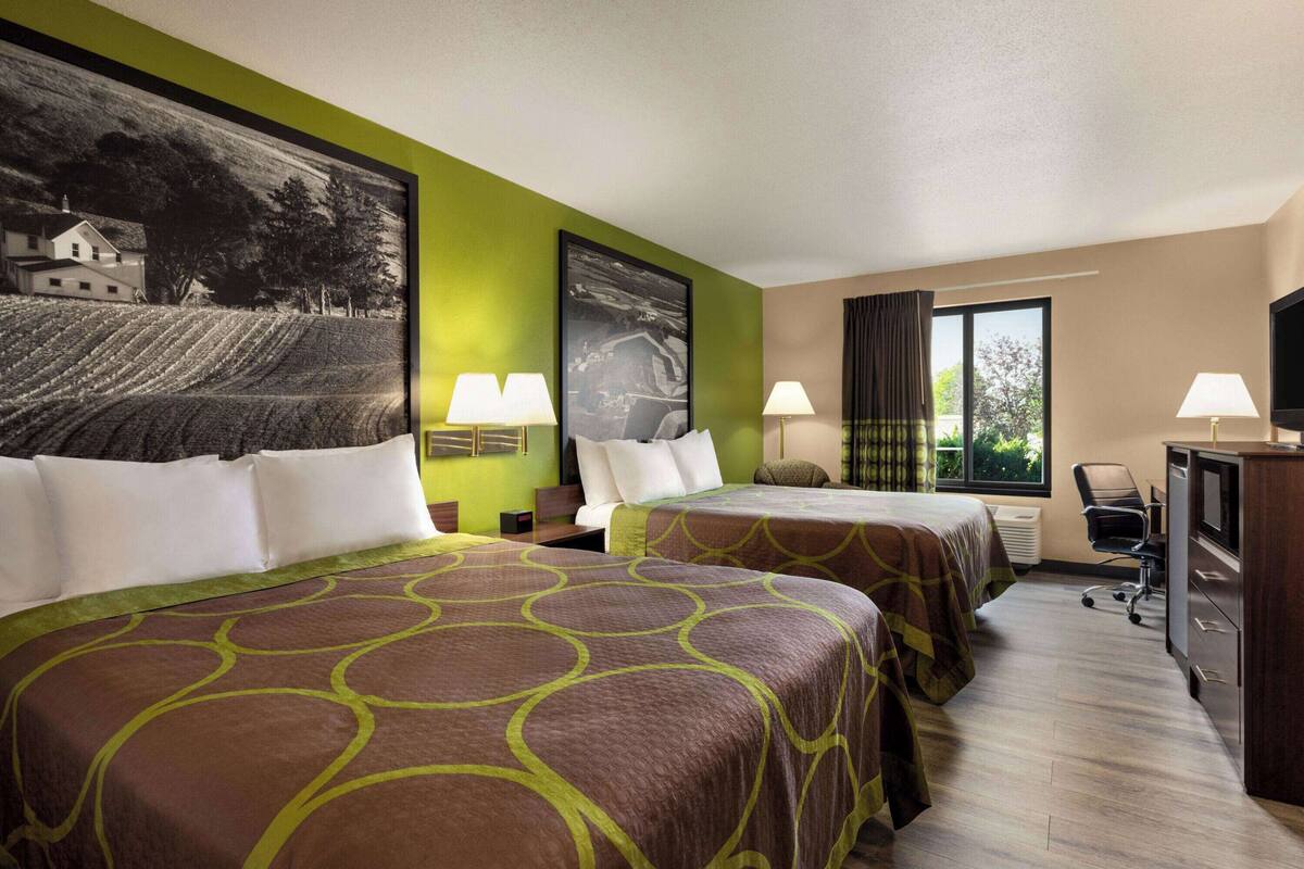 Une chambre d’hôtel avec deux lits, un bureau, une chaise et un téléviseur.