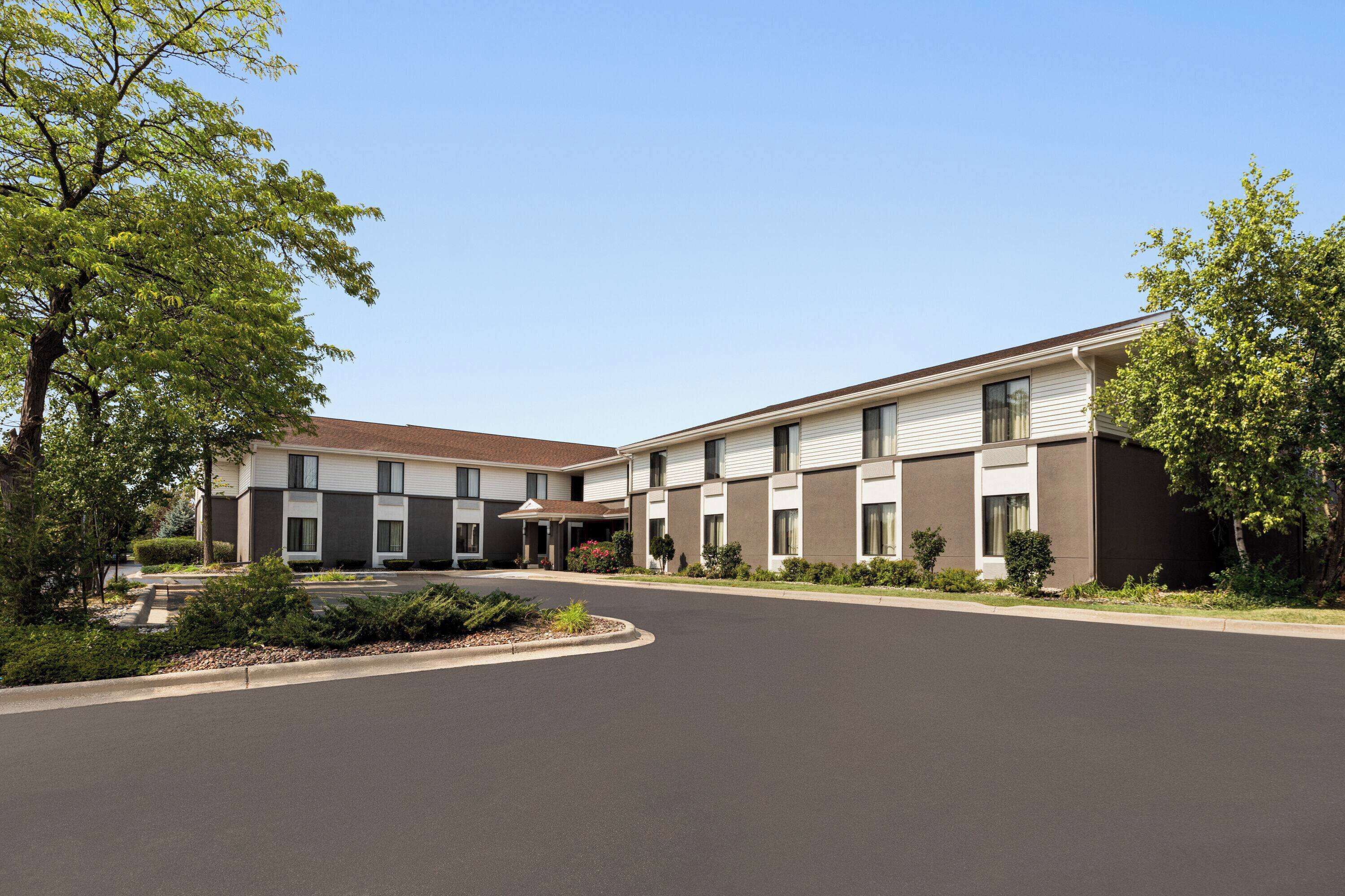A modern hotel with a central courtyard, multiple units with large windows, and a well-maintained landscape.