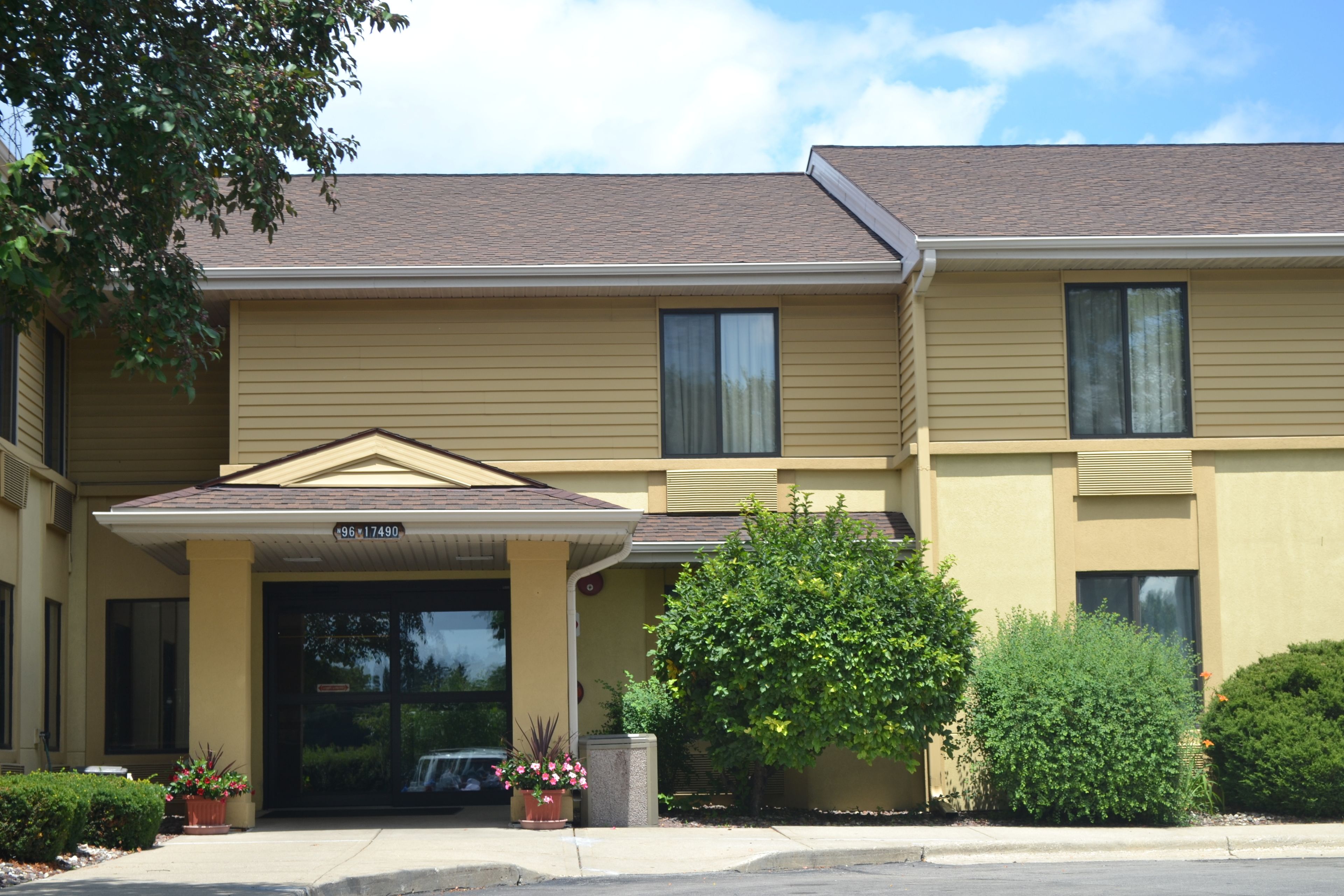 A two-story building with a beige exterior, a covered entrance, and a parking area.
