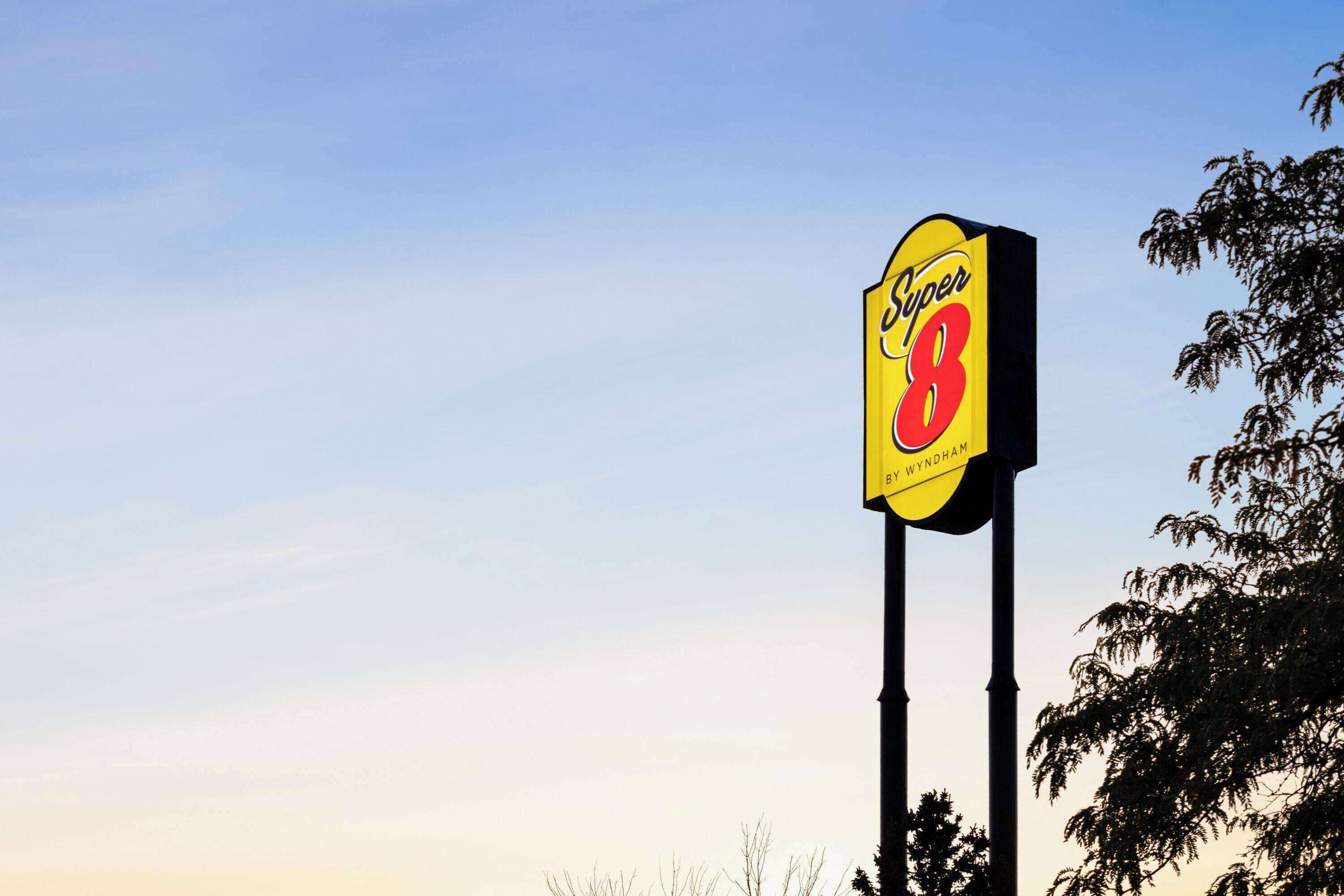 A tall sign with the text "Super 8" and "By Wyndham" against a clear sky.