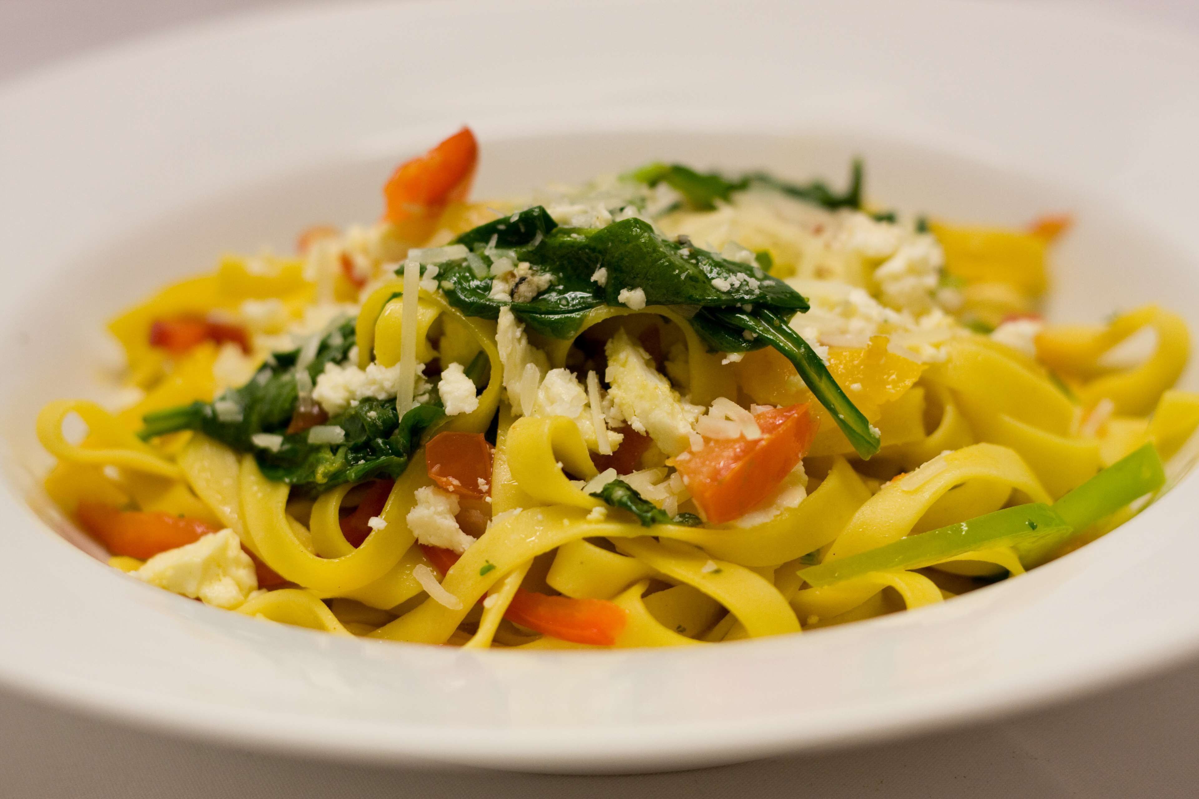 Een bord pasta met groenten en kaas.