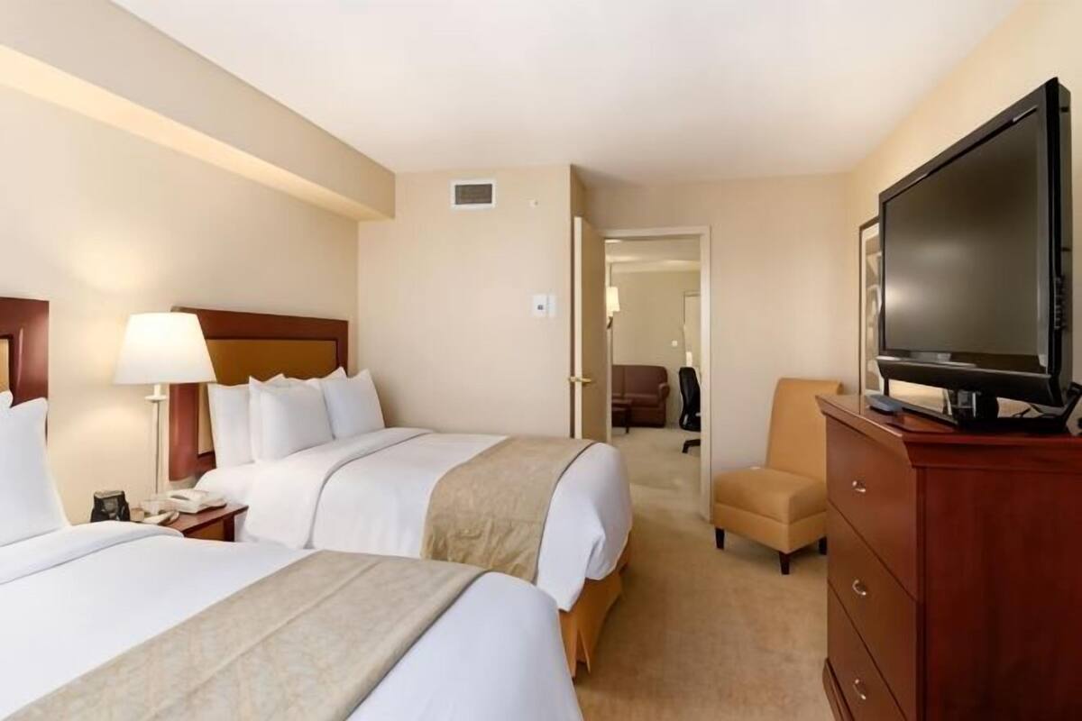 A hotel room with two beds, a television, a desk, and a chair.