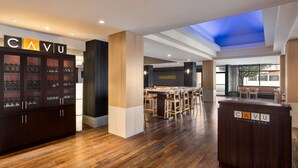 A modern kitchen bar area with a wooden floor, a bar counter, and a ceiling skylight. - Hilton Vancouver Airport (Richmond)