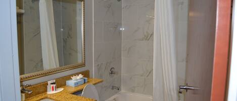 A bathroom with a marble-tiled shower, a white sink, and a toilet.