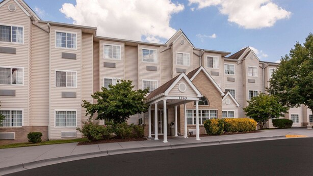 A multi-story hotel with a covered entrance, large windows, and a landscaped front yard. - Microtel Inn & Suites by Wyndham Baltimore BWI Airport (Linthicum Heights)
