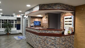 A reception area with a brick-patterned counter, a television screen, and a door with a sign. - Microtel Inn & Suites by Wyndham Baltimore BWI Airport (Linthicum Heights)