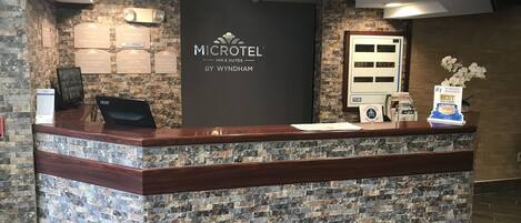 Una recepción con fachada de piedra, un letrero de Microtel Inn & Suites y una exhibición de premios.
