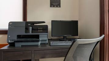 Un centre de negocis amb una impressora Hewlett-Packard, un monitor i un teclat sobre una taula.
