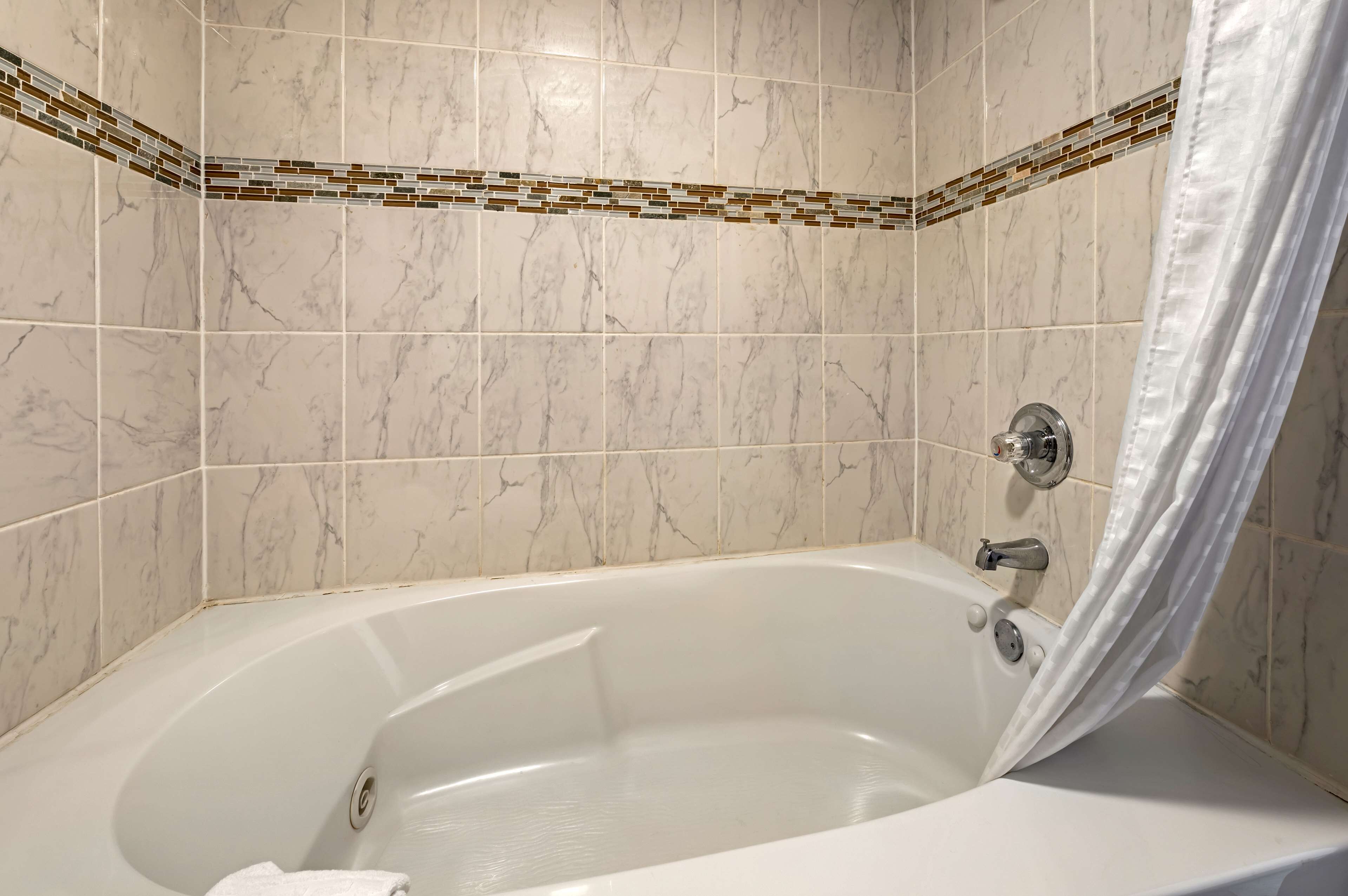 A bathroom with a freestanding bathtub, tiled walls, and a shower curtain.