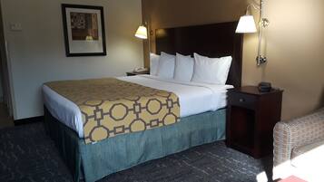 A hotel room with a bed, two bedside lamps, a nightstand with a phone, a framed picture on the wall, and a patterned carpet.