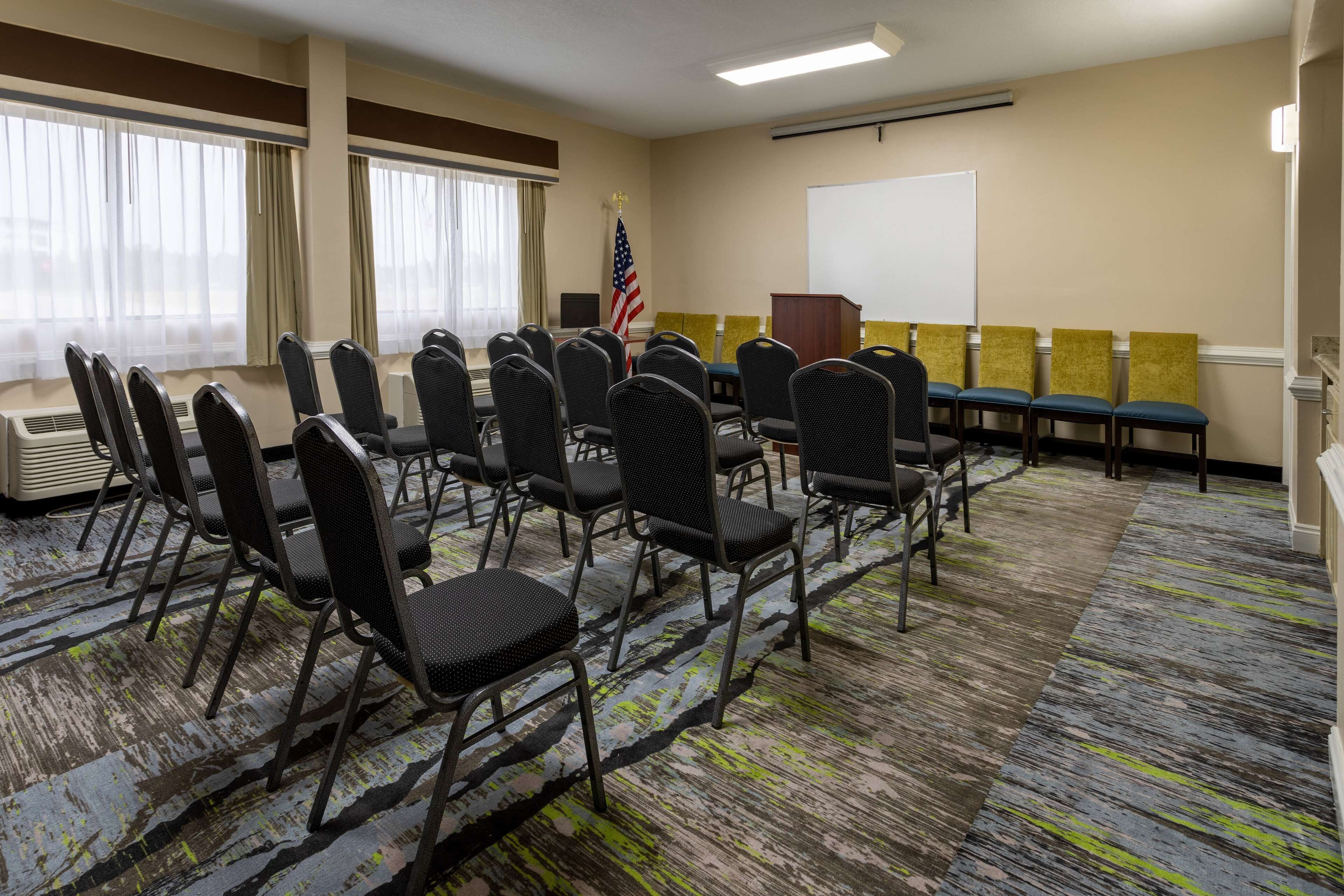A conference room with rows of chairs, a podium, a whiteboard, and an American flag.