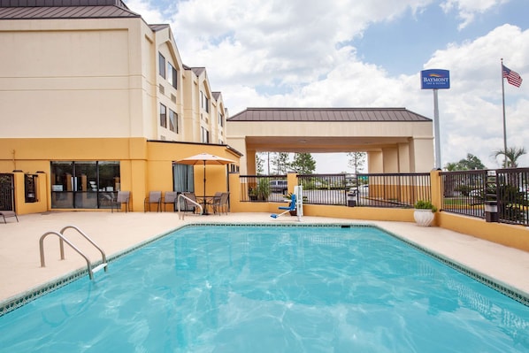 A hotel with a swimming pool, outdoor seating, and a covered area.