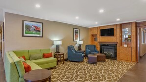 Ein Wohnzimmer mit einem grünen Sofa, blauen Sesseln, einem Kamin und einem Fernseher.