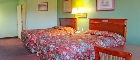 A double bed with floral bedding, a nightstand, a chair, and two wall-mounted lamps.