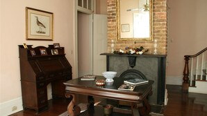Quarto com escrivaninha de madeira, lareira, quadro na parede e escada.