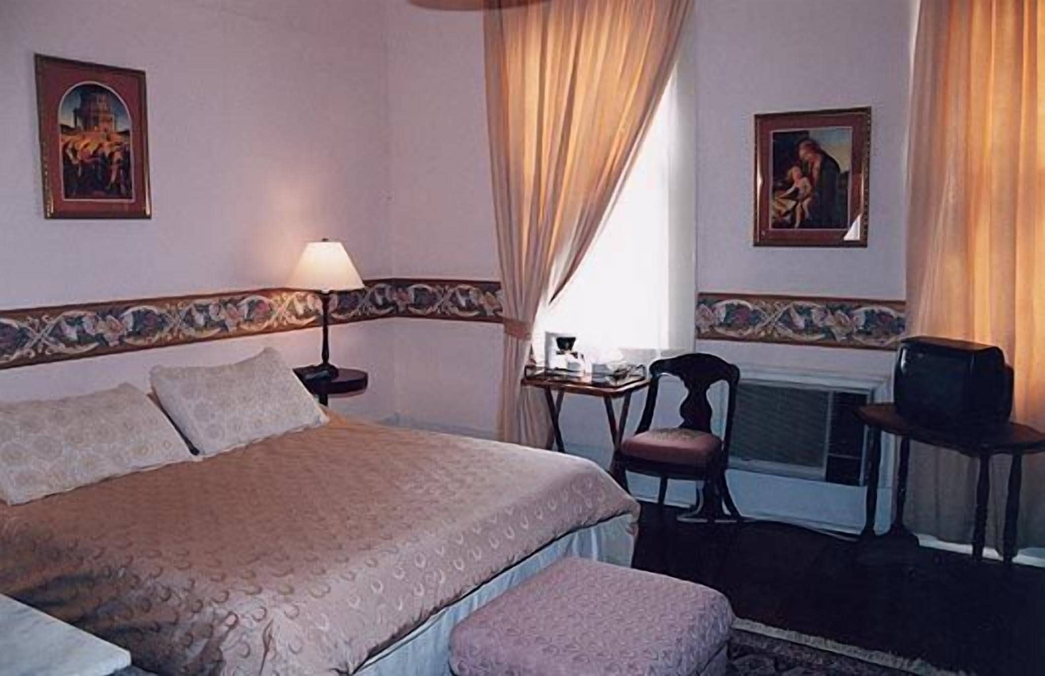 Une chambre d’hôtel avec un lit, une chaise, une table avec une lampe et un téléviseur.