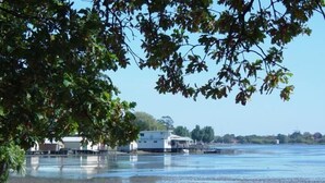 A waterfront property with a dock, a boat, and a building with a white roof. - Central City Motor Inn (Bakery Hill)