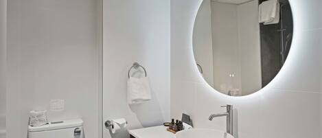 Un baño moderno con inodoro, lavamanos, espejo y toallero.