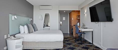 Una habitación de hotel con cama, escritorio, silla, televisor y baño.