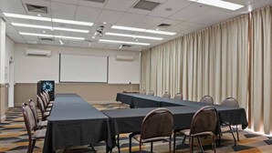 A conference room with a long table, chairs, a projector screen, and a clock. - The Gladstone (Gladstone)