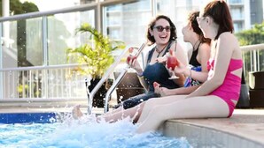 Three people sitting by a pool with water splashing around them. - The Gladstone (Gladstone)