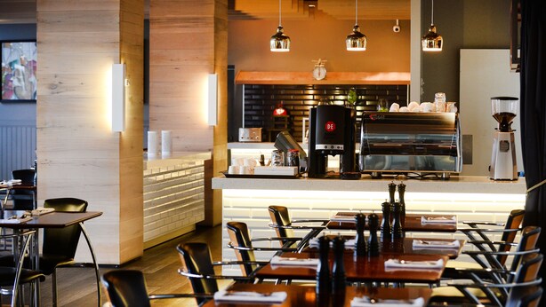 A modern cafe with wooden accents, a coffee bar, and seating for guests. - The Gladstone (Gladstone)