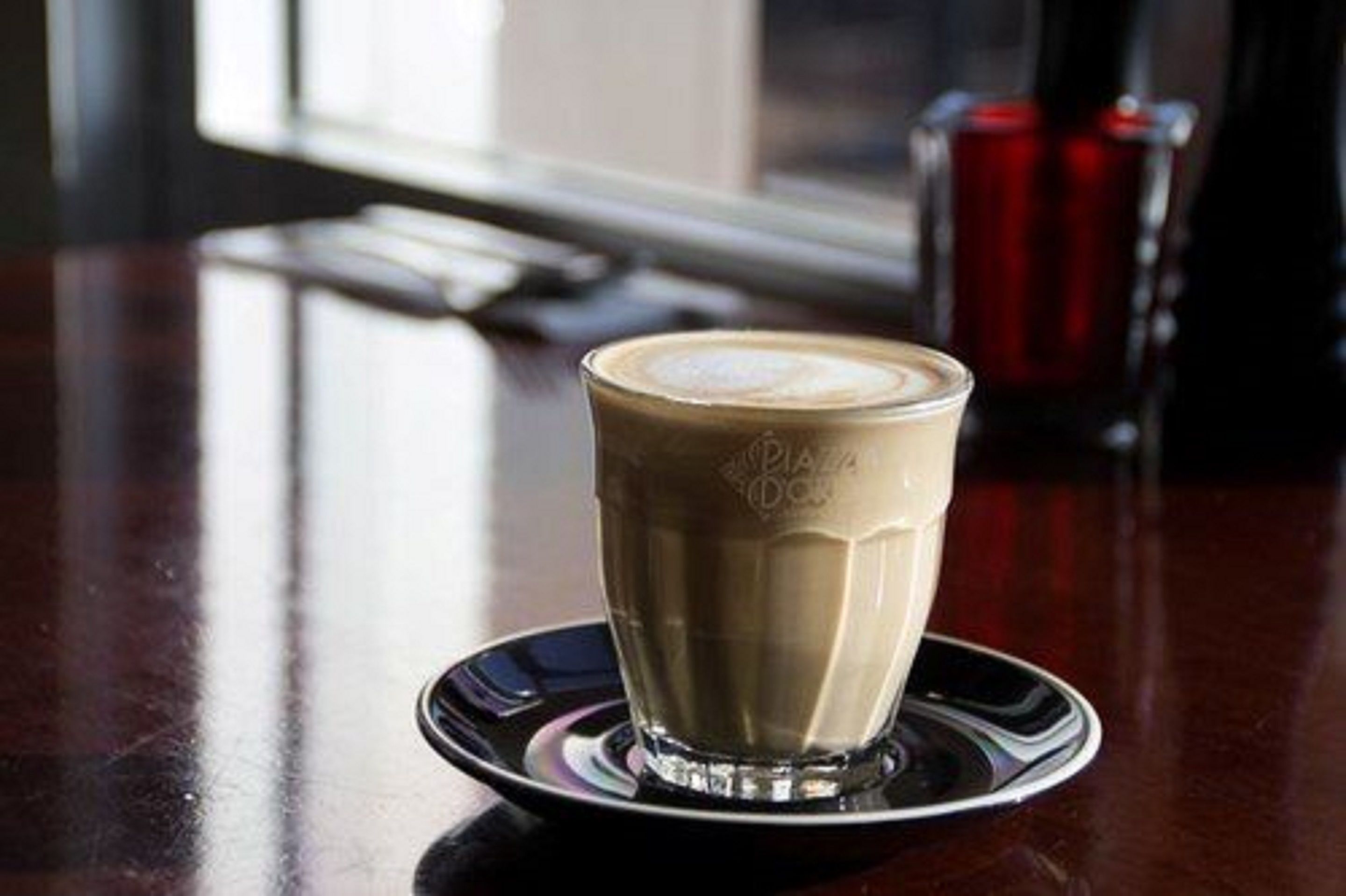 Una taza de café sobre un plato con un fondo desenfocado.