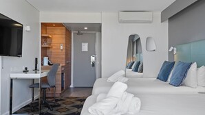 A hotel room with a bed, a desk, a chair, a television, and a bathroom visible through an open door. - The Gladstone (Gladstone)