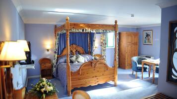 A four-poster bed with a canopy, a wooden desk, a chair, and a cabinet in a room with light blue walls.