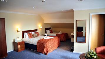 Een hotelkamer met twee bedden, een tafeltje met een bloevas, een spiegel en een houten garderobe.