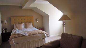 A hotel room with a large bed, a nightstand, a lamp, and a chair.