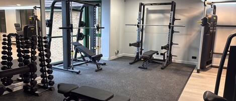 Ein Fitnessstudio mit Gewichten, Bänken und Kurzhanteln.